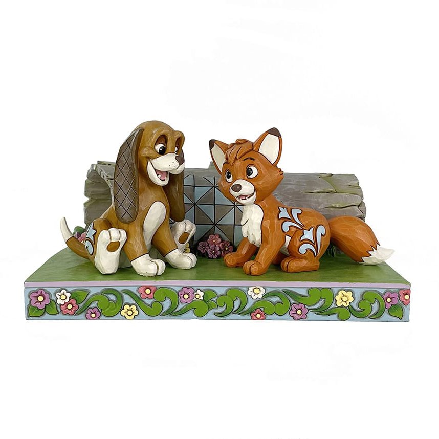 Enesco Jim Shore-beeldje van de vos en de jachthond die samen spelen in een bos, met kenmerkende rosemaling-, patchwork- en bloemendetails.